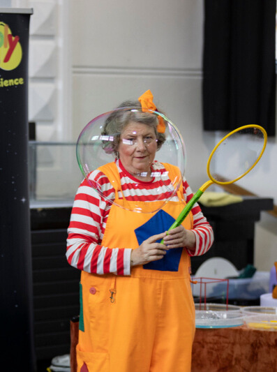 Bubbly Maths entertainer in orange dungarees holding a giant soap bubble