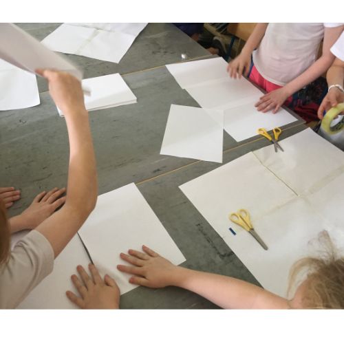 Bits of paper of different sizes on a table while children were building and testing paper airplanes of different sizes.