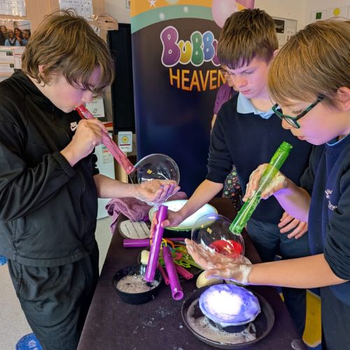 A group of children making amazing bubbles during a bubble science workshop