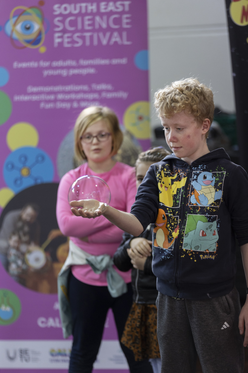 Bubbly Maths and Science entertainer with children holding a bubble at the South East Science Festival